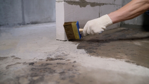 Construction,worker,applying,a,waterproofing,membrane,to,a,concrete,floor